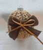 Handmade knit Christmas ornament with brown ribbon bow on a neutral background