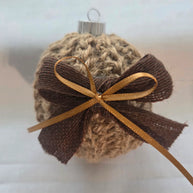 Handmade knit Christmas ornament with brown ribbon bow on a neutral background