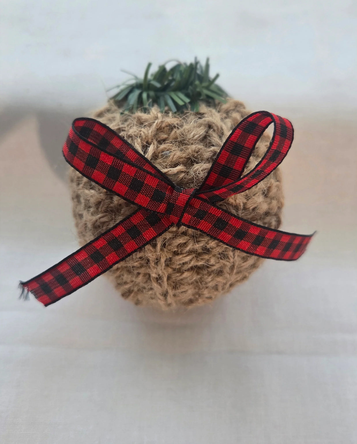Rustic Christmas ornament with jute twine, red plaid ribbon bow, and faux greenery top