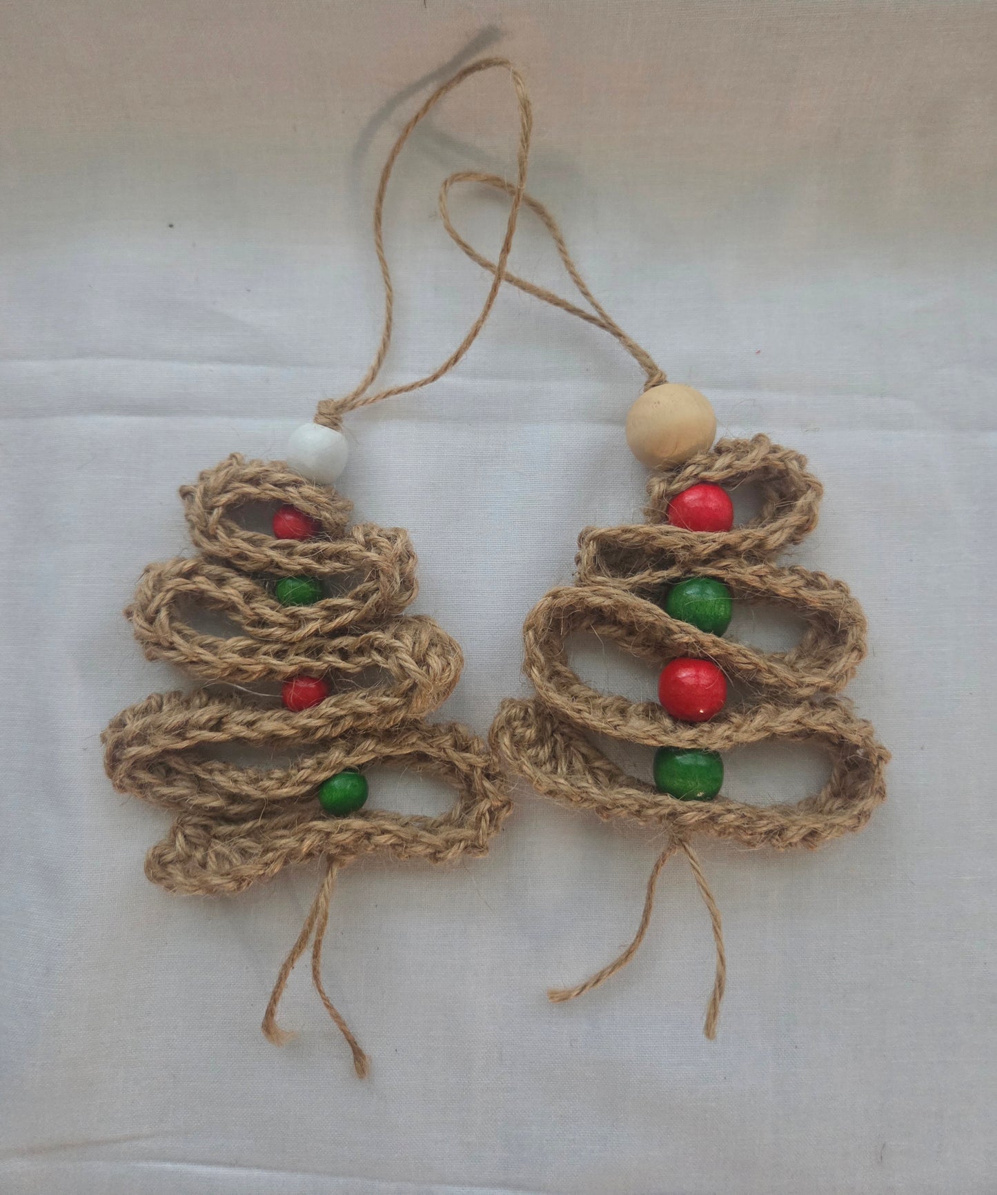 Handmade jute Christmas tree ornaments with red and green beads on white background