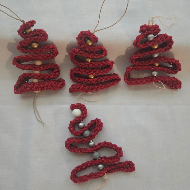 Handmade red crochet Christmas tree ornaments with beads on white background