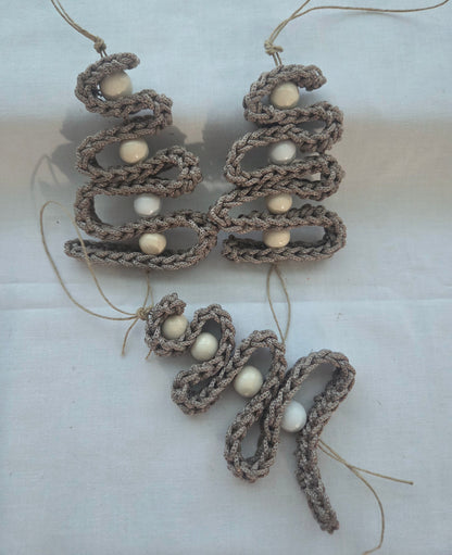 Handmade crochet ornaments with beige yarn and white beads on white fabric background