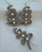 Handmade crochet ornaments with beige yarn and white beads on white fabric background