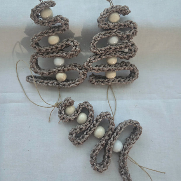 Handmade crochet ornaments with beige yarn and white beads on white fabric background