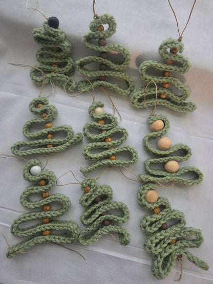 Handmade crochet Christmas tree ornaments with wooden beads on a white fabric background.