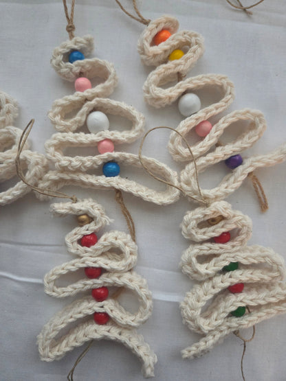 Handmade crochet Christmas tree ornaments with colorful beads on white fabric
