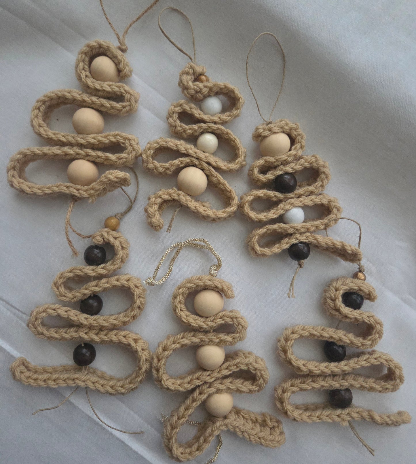 Handmade jute Christmas tree ornaments with wooden beads on white fabric