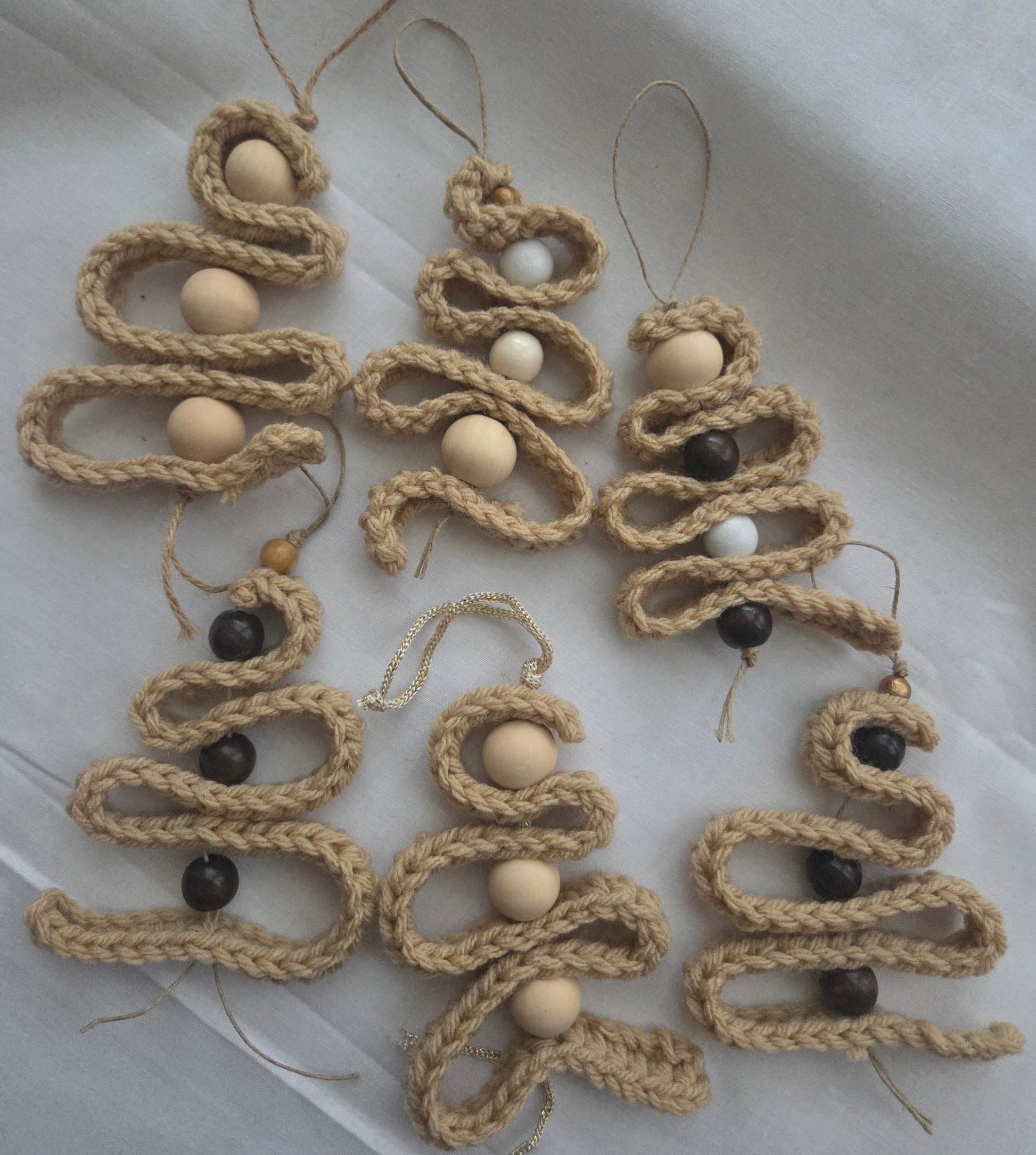Handmade jute Christmas tree ornaments with wooden beads on white fabric