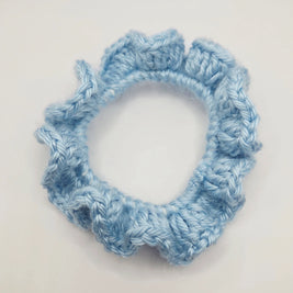 Handmade light blue crochet scrunchie on white background, cozy hair accessory
