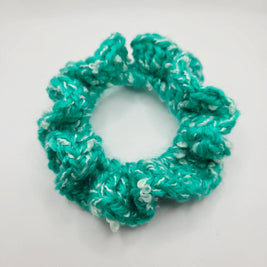 Handmade turquoise crochet scrunchie with white accents on white background