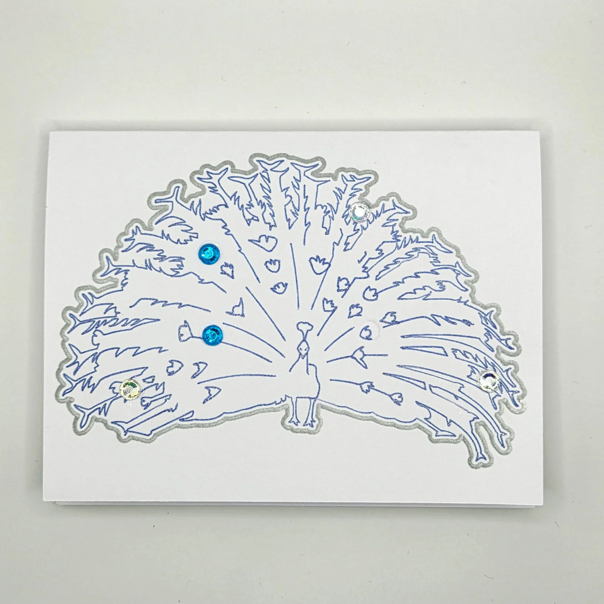 Handmade peacock card with blue outline and gemstone accents, perfect for creative gifts