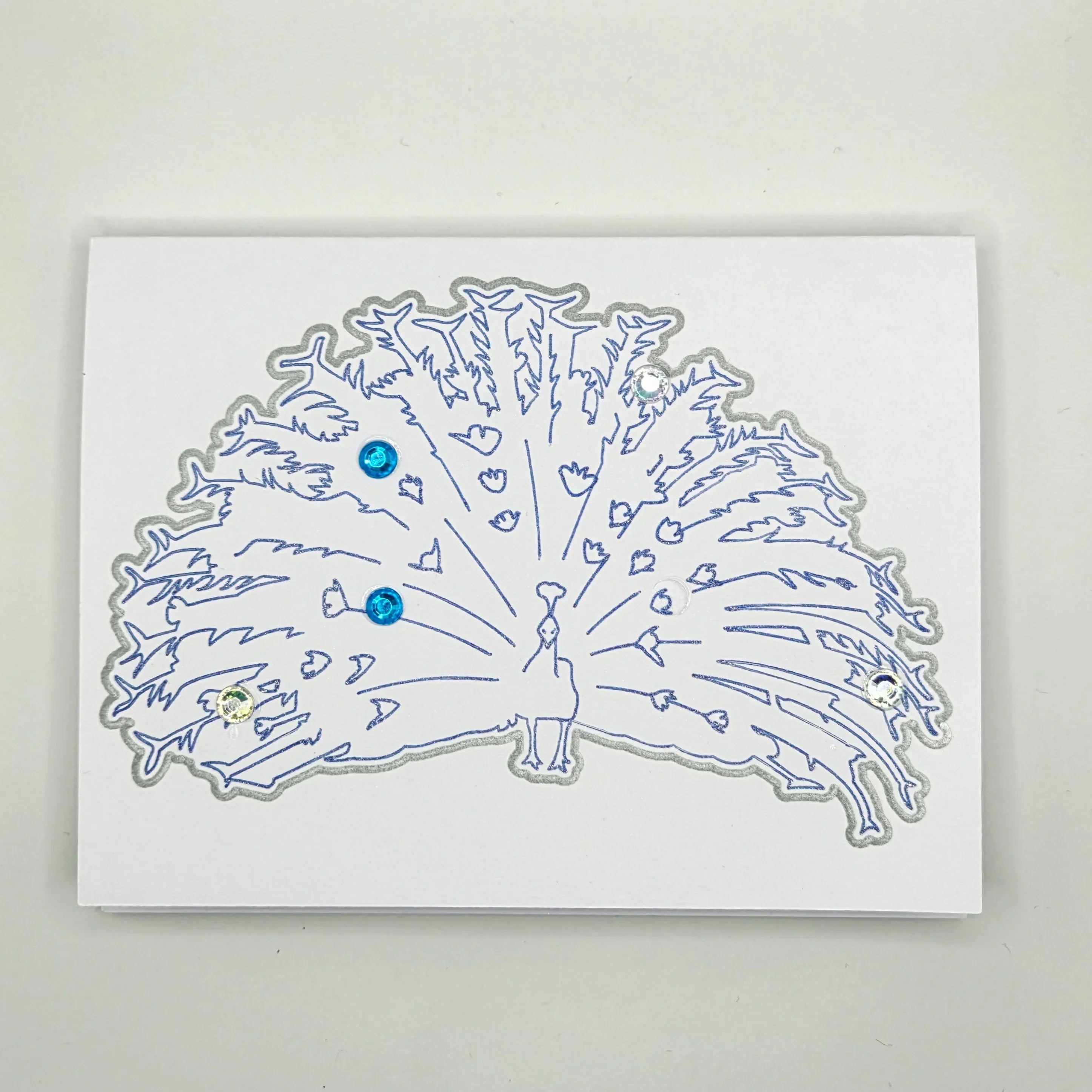 Handmade peacock card with blue outline and gemstone accents, perfect for creative gifts