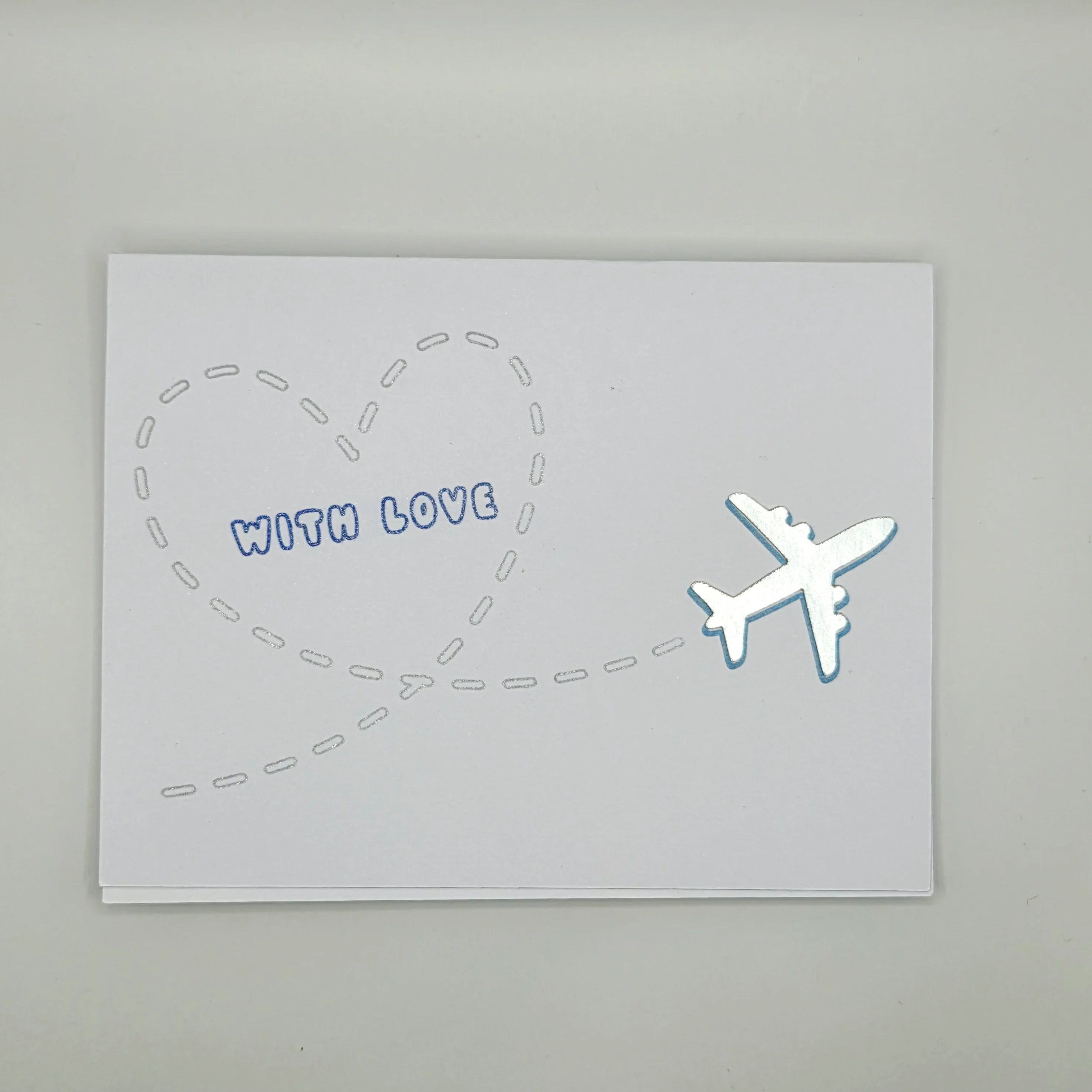 Handmade greeting card with silver airplane and heart-shaped flight path, text 'With Love'.