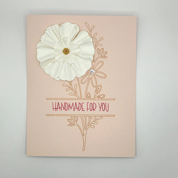 Handmade card with white paper flower, floral design, and 'Handmade for You' text on pink background.