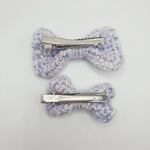 Handmade crochet bow hair clips in soft pastel yarn, perfect for cozy, creative styling.