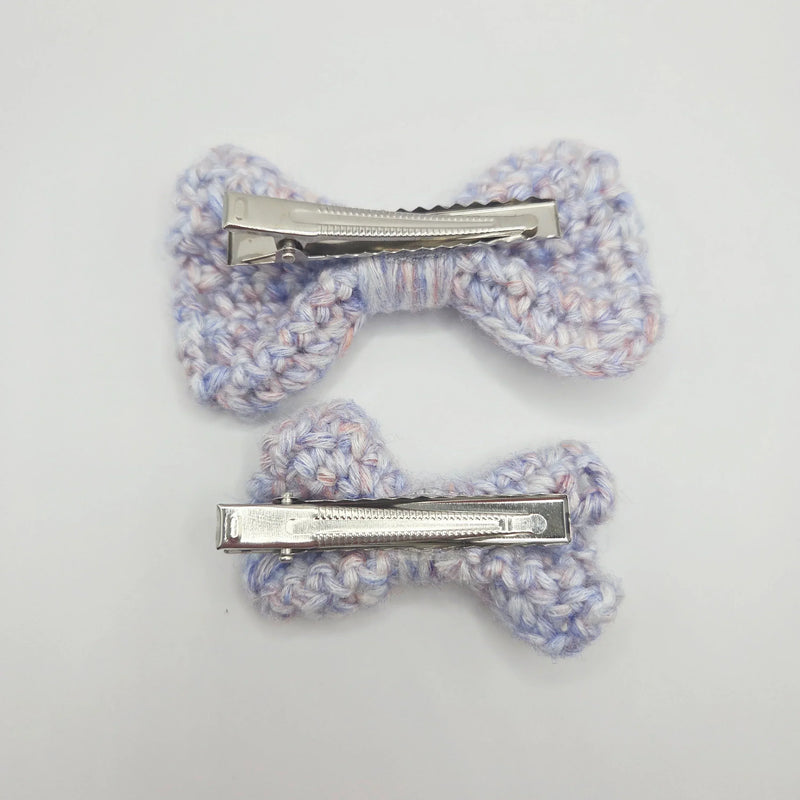 Handmade crochet bow hair clips in soft pastel yarn, perfect for cozy, creative styling.