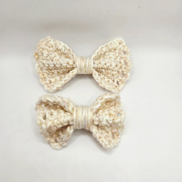 Handmade crochet cream bows on white background, cozy gift by Erika Liesel