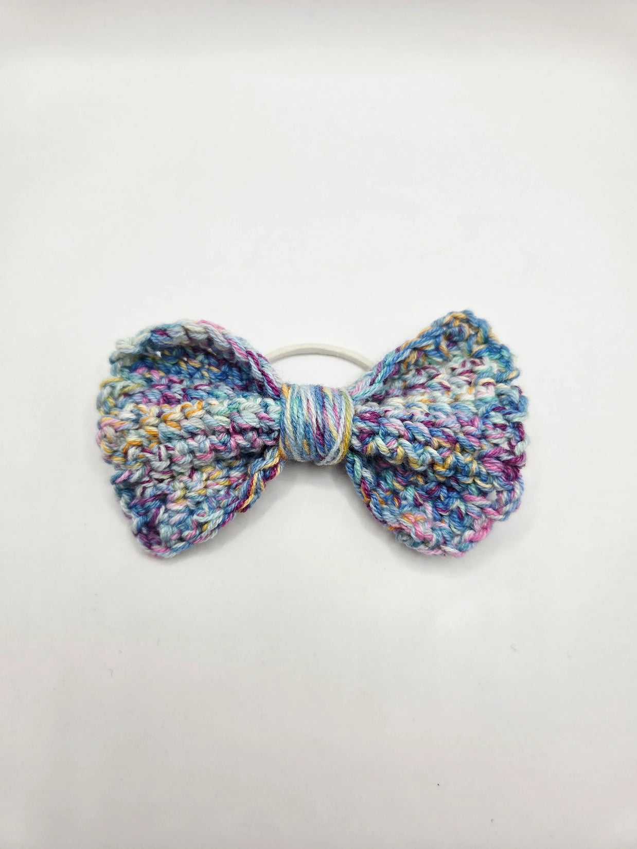 Handmade crochet bow hair tie in pastel multicolor yarn, cozy and creative accessory