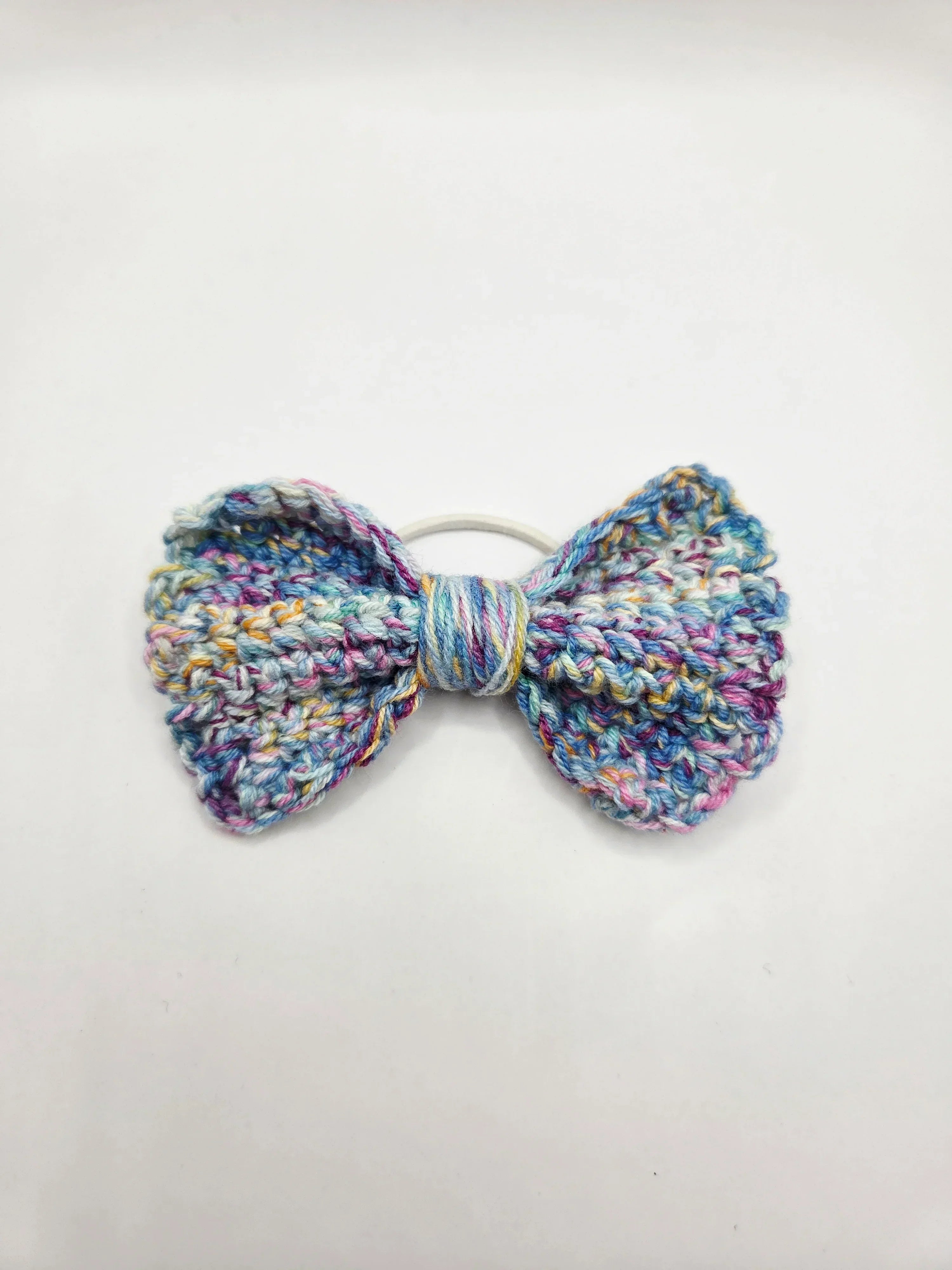 Handmade crochet bow hair tie in pastel multicolor yarn, cozy and creative accessory