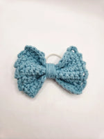 Handmade crochet bow hair tie in soft blue, cozy and creative accessory for everyday wear