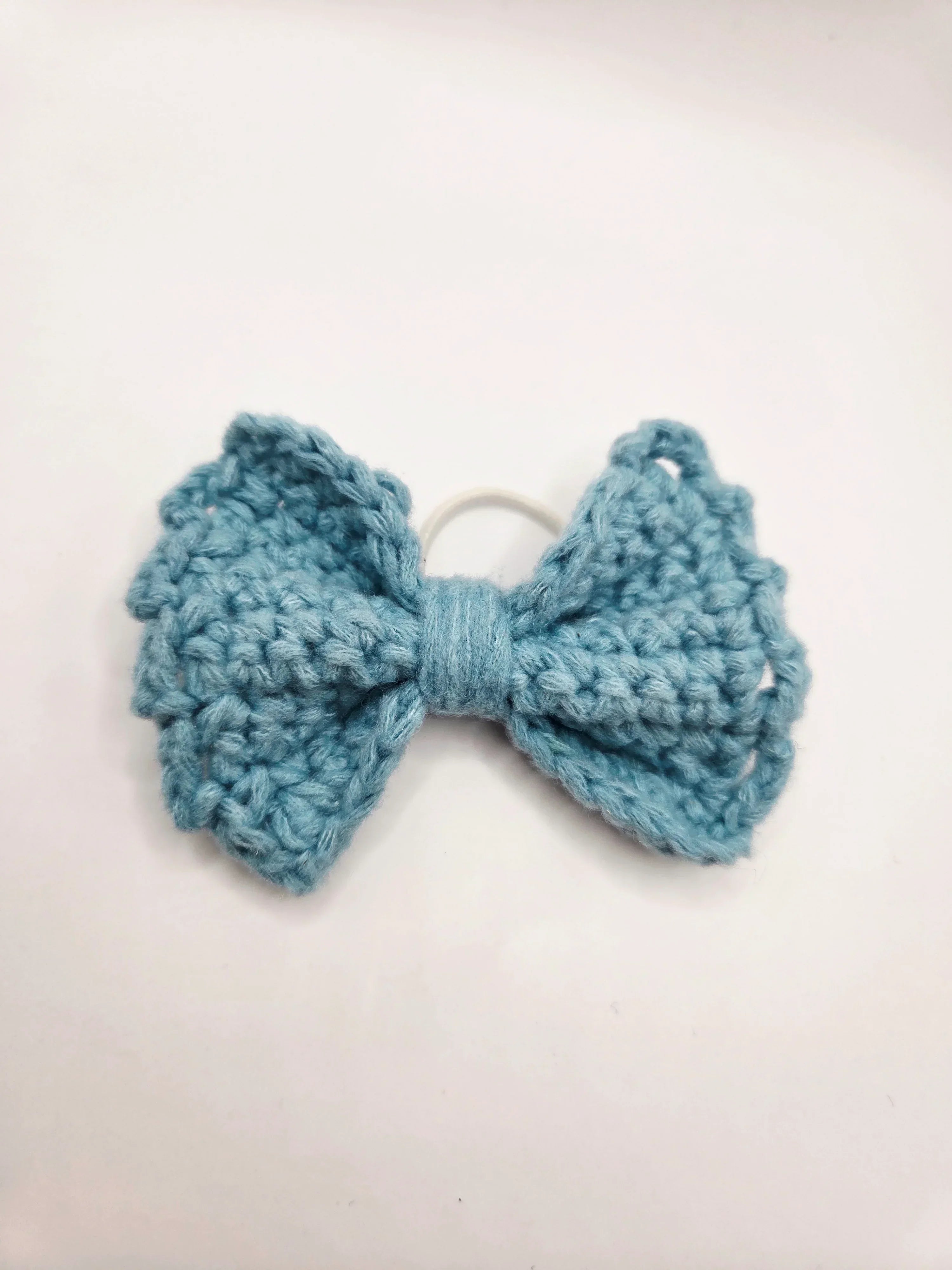 Handmade crochet bow hair tie in soft blue, cozy and creative accessory for everyday wear
