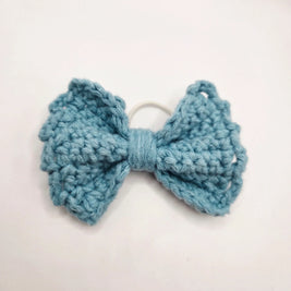 Handmade crochet bow hair tie in soft blue, cozy and creative accessory for everyday wear