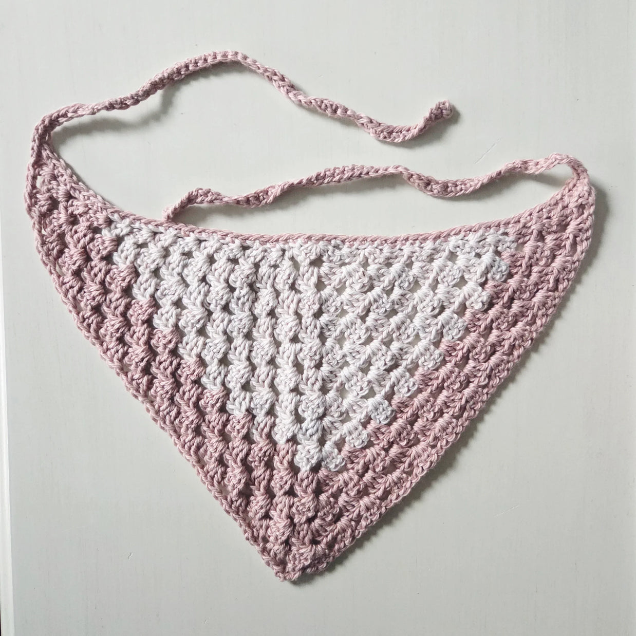 Handmade crochet triangle scarf in pink and white, perfect for cozy, creative gifting.