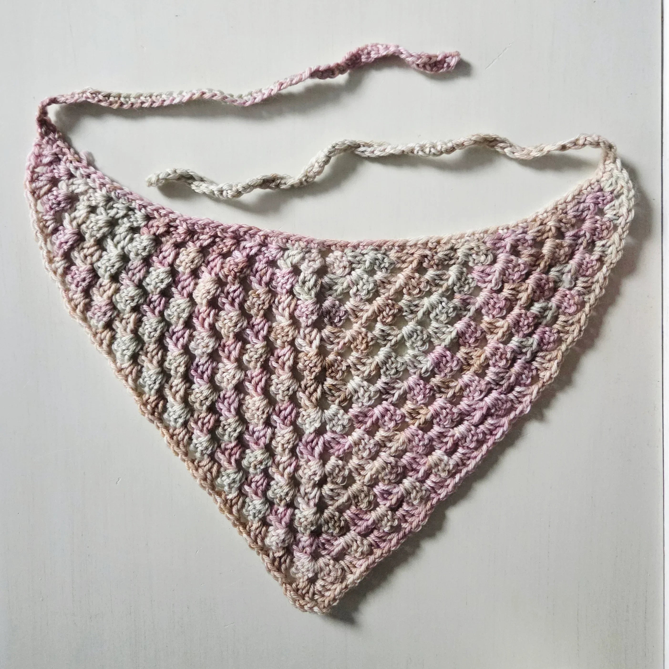 Handmade crochet triangle scarf in soft pink and gray tones, perfect for cozy everyday wear.
