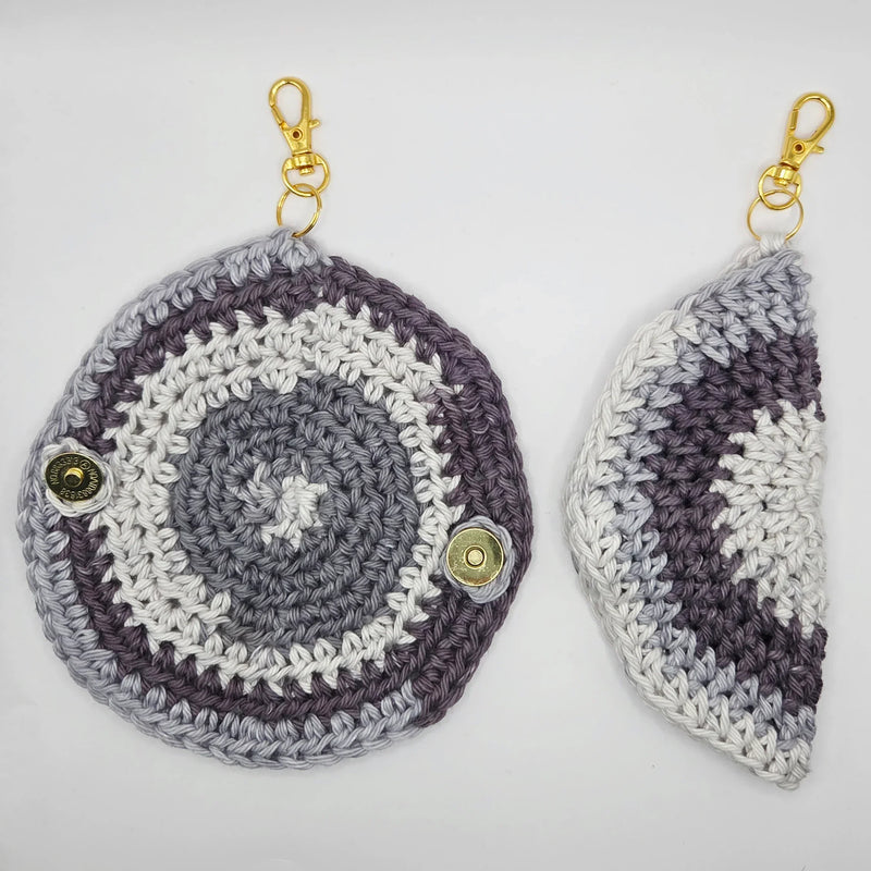Handmade crochet keychains in gray and white, featuring gold clasps and button details for cozy, creative gifts.