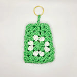 Green crocheted keychain with white flower design, handmade crochet gift for everyday coziness