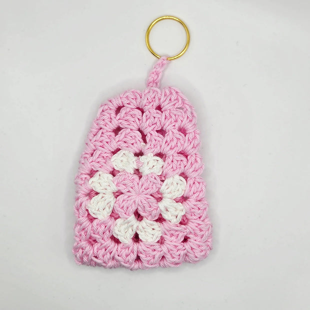 Pink and white handmade crochet keychain with floral pattern on white background