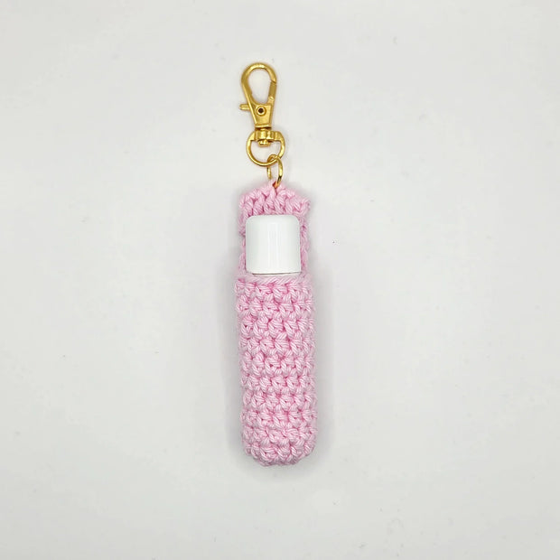 Handmade pink crochet lip balm holder with gold keychain clip on white background