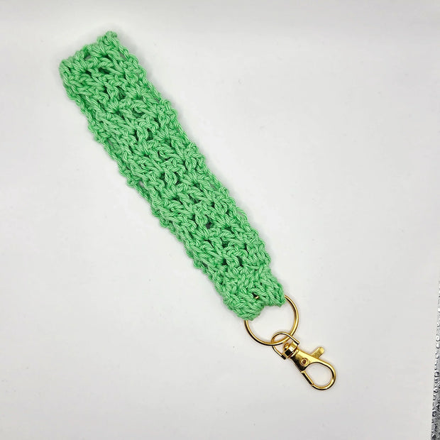 Handmade green crochet keychain wristlet with gold clasp on white background