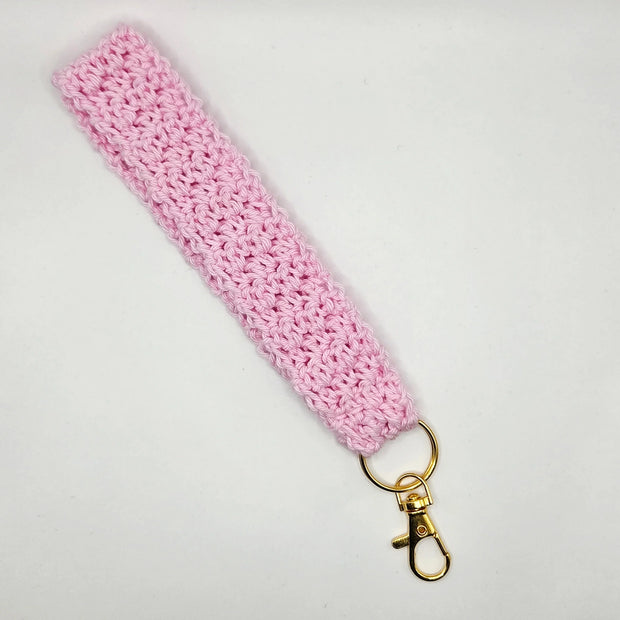 Handmade pink crochet keychain wristlet with gold clasp on white background