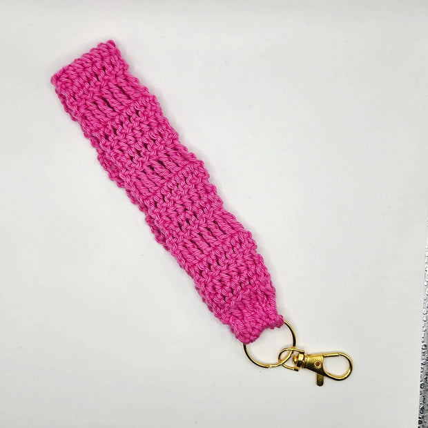 Handmade pink crochet keychain wristlet with gold clasp on white background