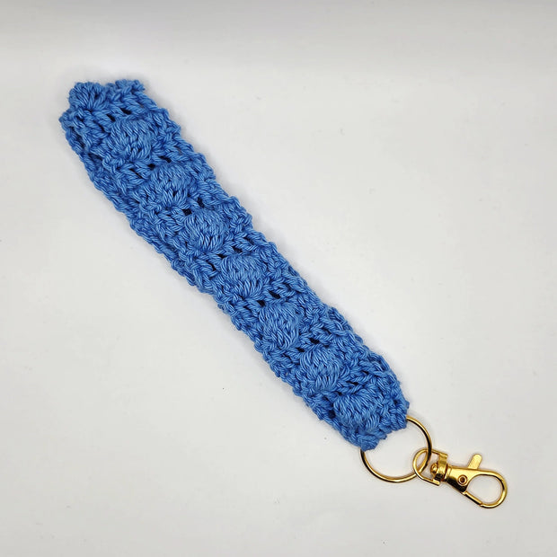 Handmade blue crochet keychain wristlet with gold clasp on white background