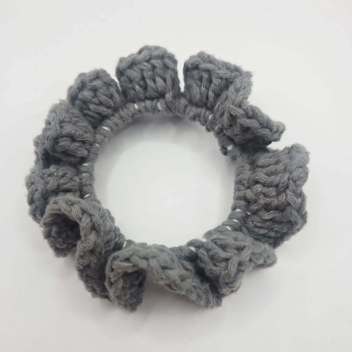 Handmade grey crochet scrunchie with ruffled edges on white background