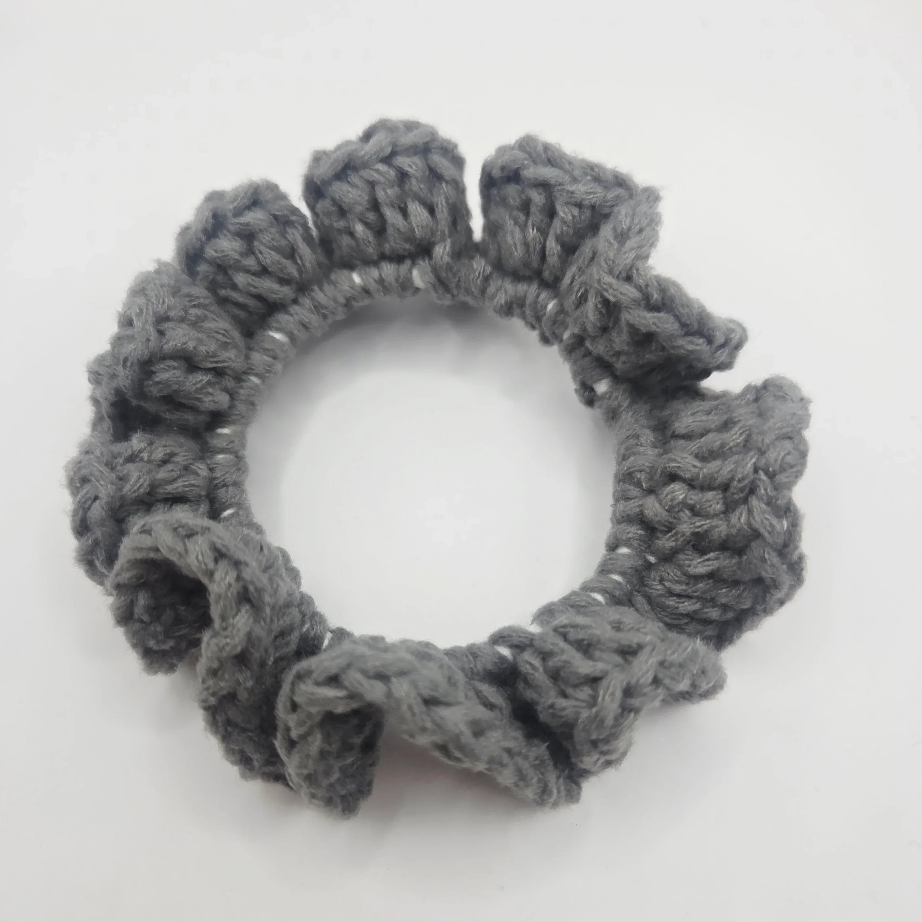 Handmade grey crochet scrunchie with ruffled edges on white background