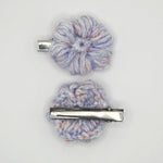 Handmade crochet flower hair clips in pastel blue, pink, and white yarn, perfect for cozy, creative styling.