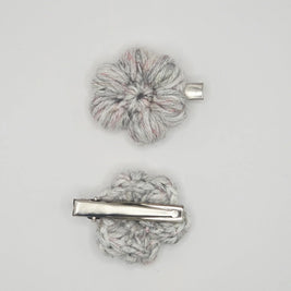 Handmade crochet flower hair clips in light grey yarn on a plain background