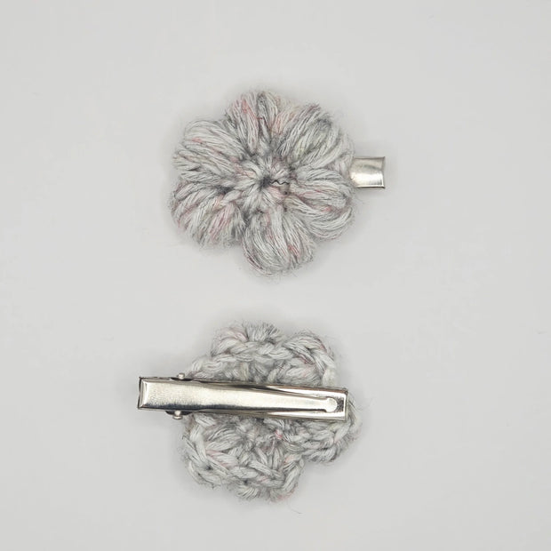Handmade crochet flower hair clips in light grey yarn on a plain background