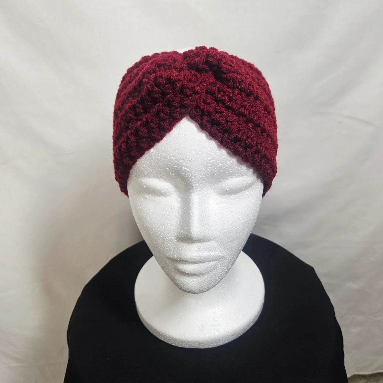 Handmade burgundy crochet headband on a white mannequin, cozy winter accessory
