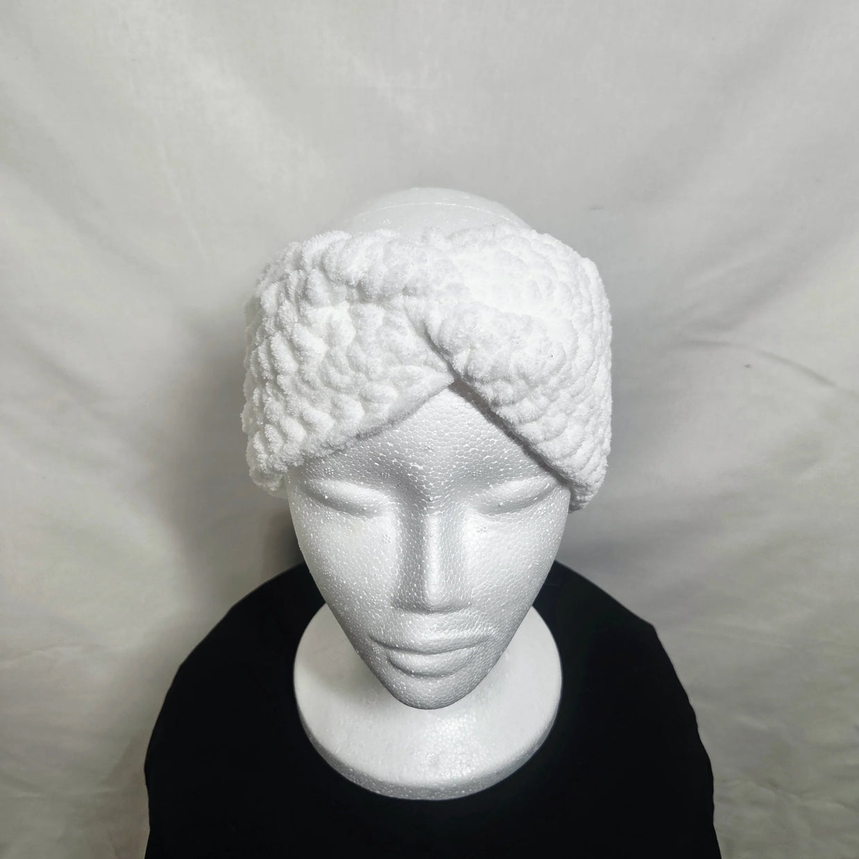 Handmade white crochet headband displayed on a mannequin, cozy winter accessory