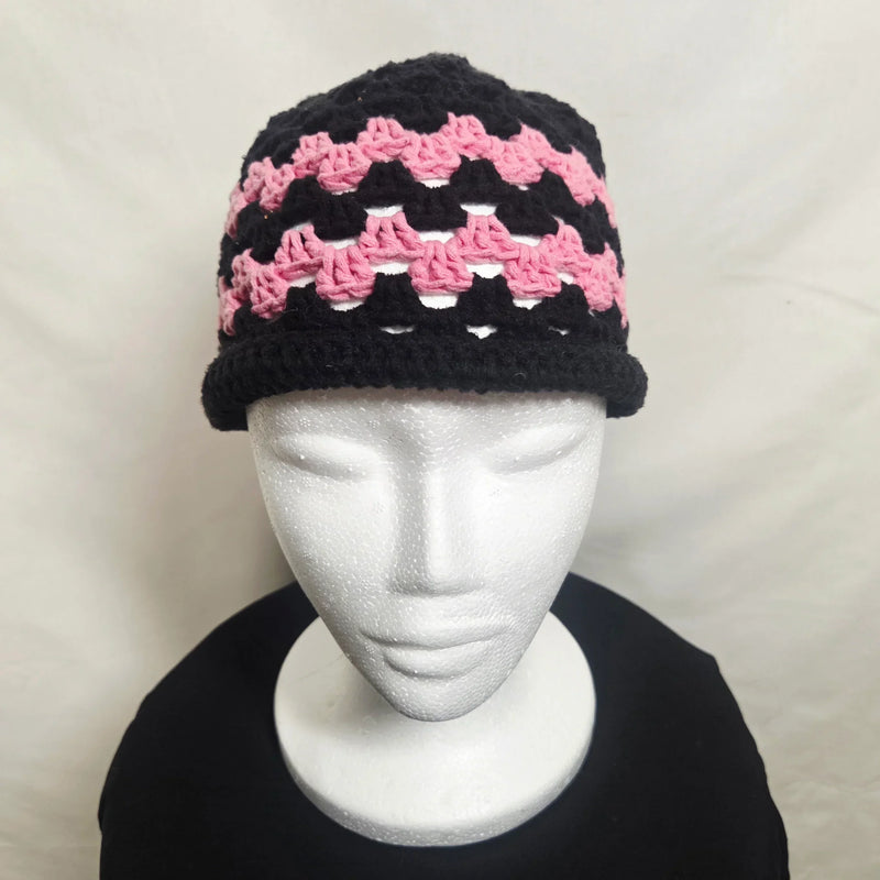 Handmade crochet hat with black, pink, and white geometric pattern on mannequin head