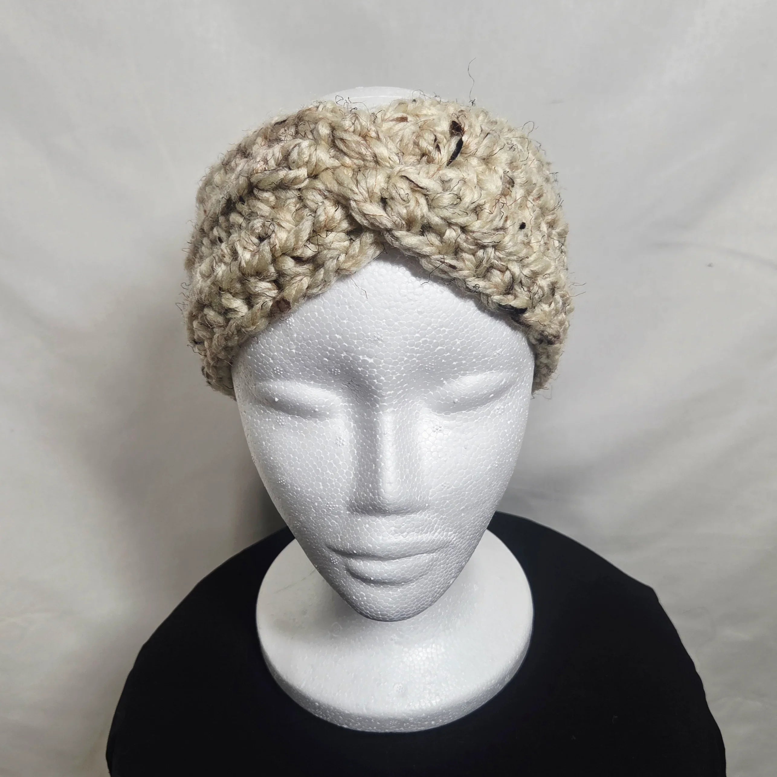 Handmade chunky crochet headband in beige yarn on a display mannequin