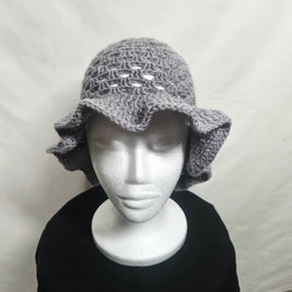 Handmade gray crochet ruffle hat on mannequin, cozy accessory by Erika Liesel