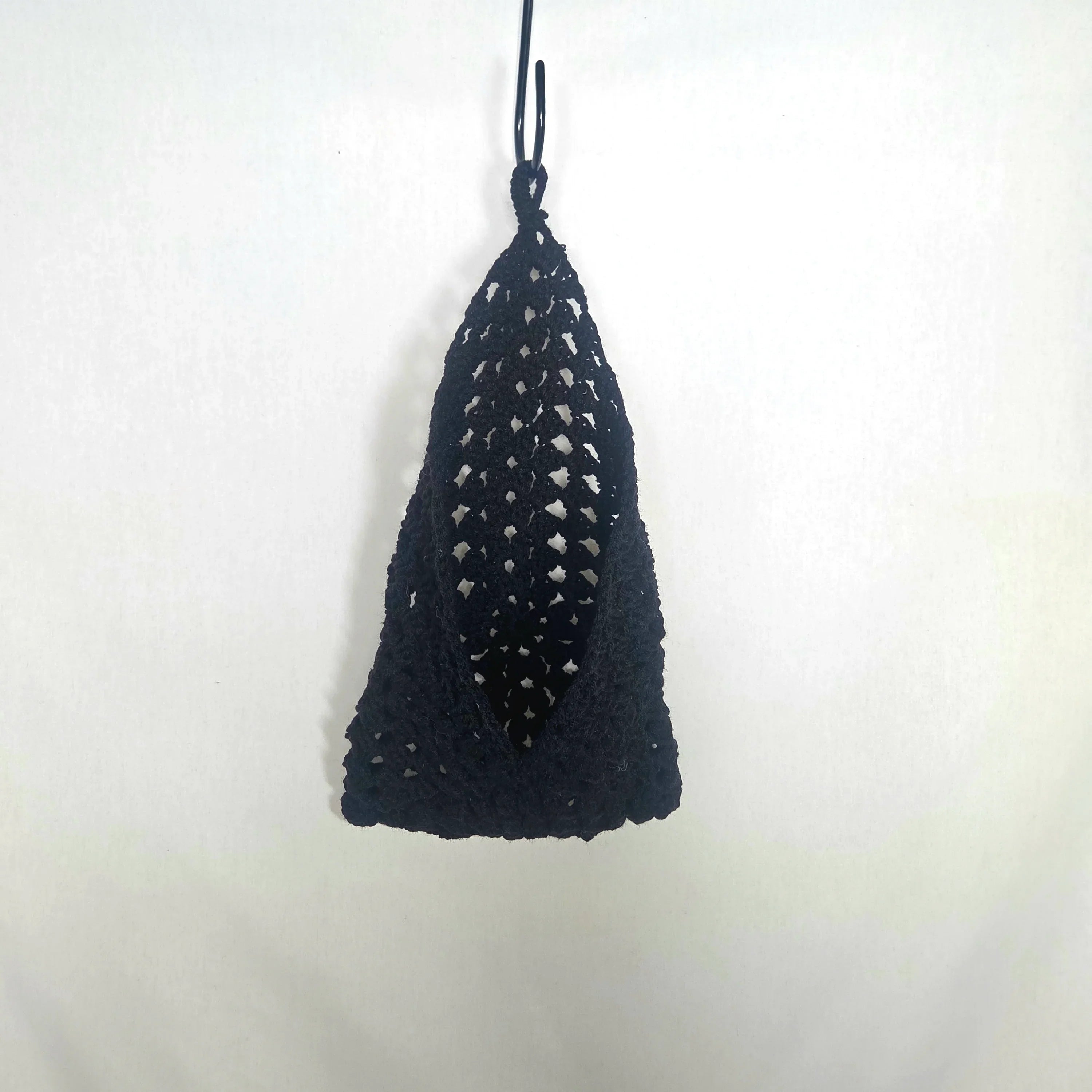 Handmade black crochet bag hanging on white background, cozy gift by Erika Liesel