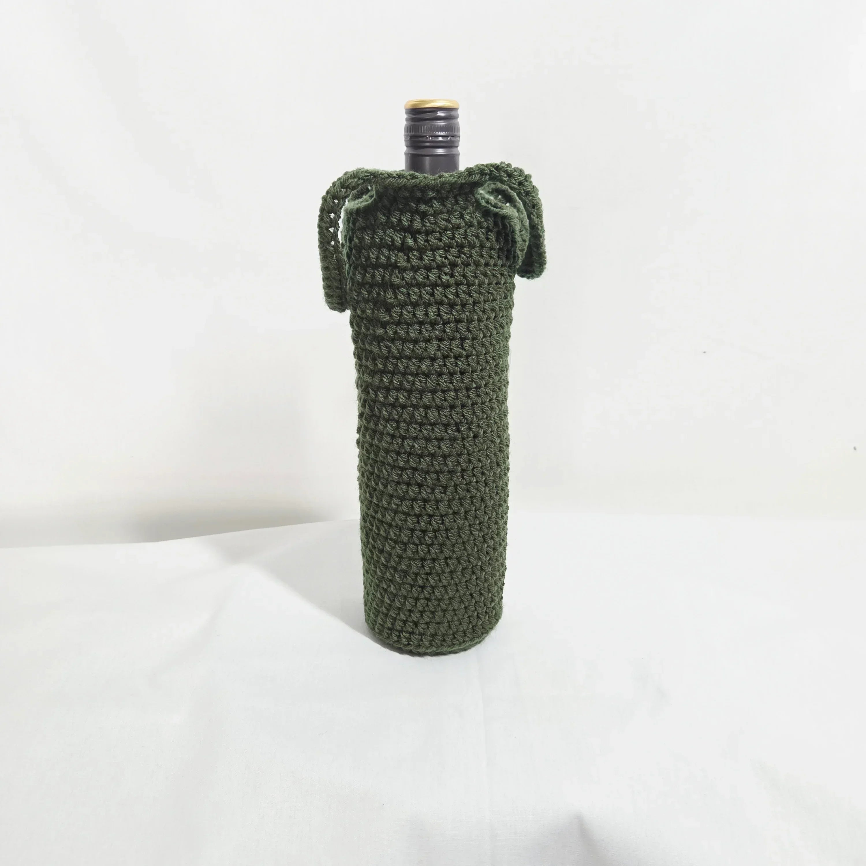 Handmade crochet bottle cover in dark green, displayed upright on a white background.