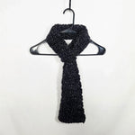 Handmade black crochet scarf draped on hanger, cozy winter accessory for warmth and style