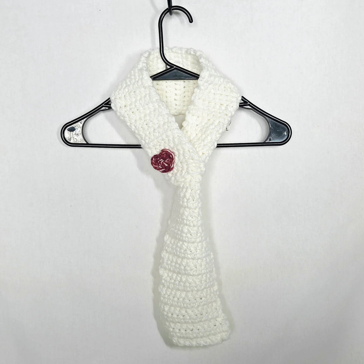 Handmade white crochet scarf with red rose accent on hanger, cozy gift by Erika Liesel